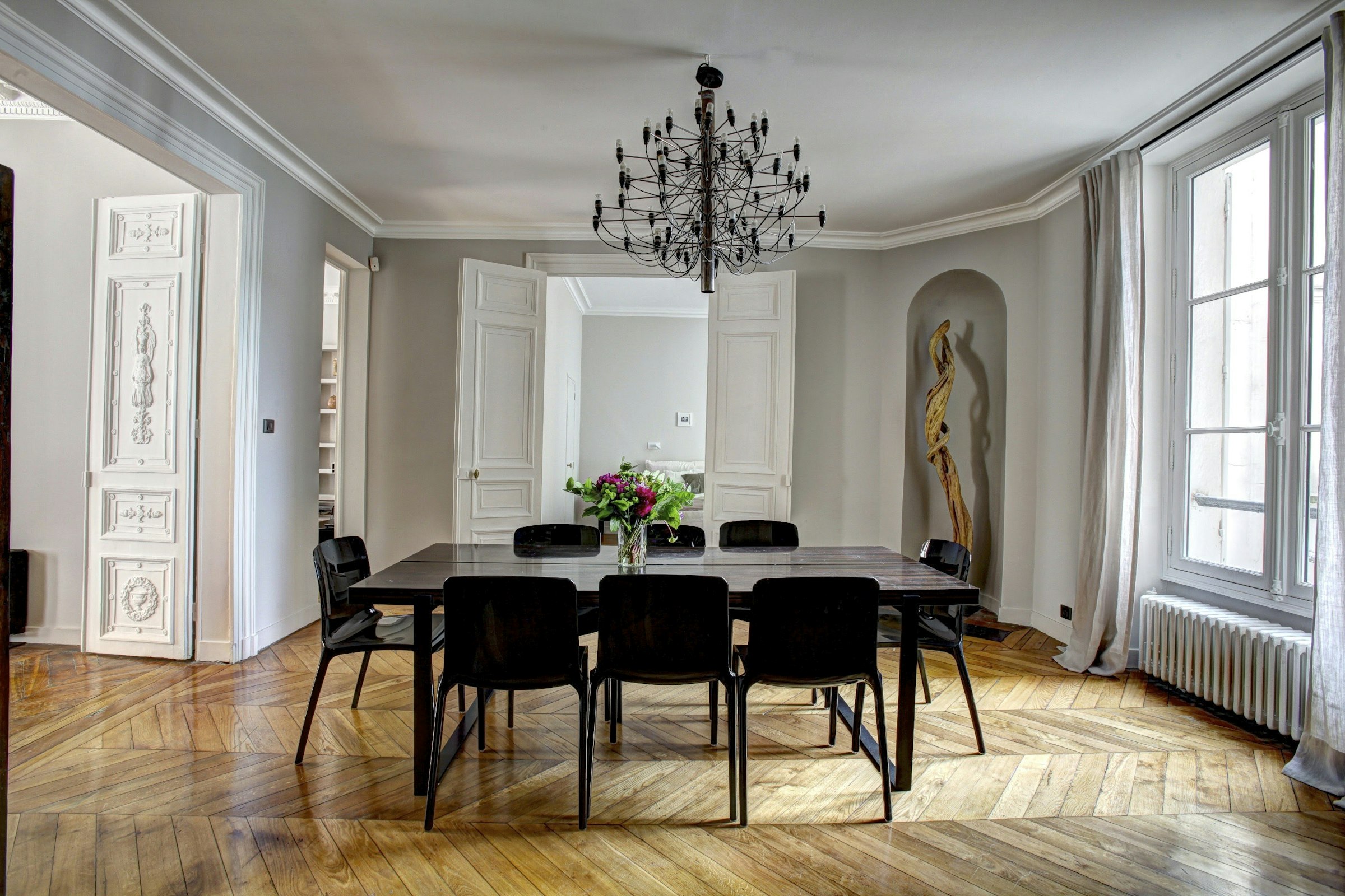 Salle à manger d'un appartement ancien : parquet en chevron, moulures et grandes fenêtres